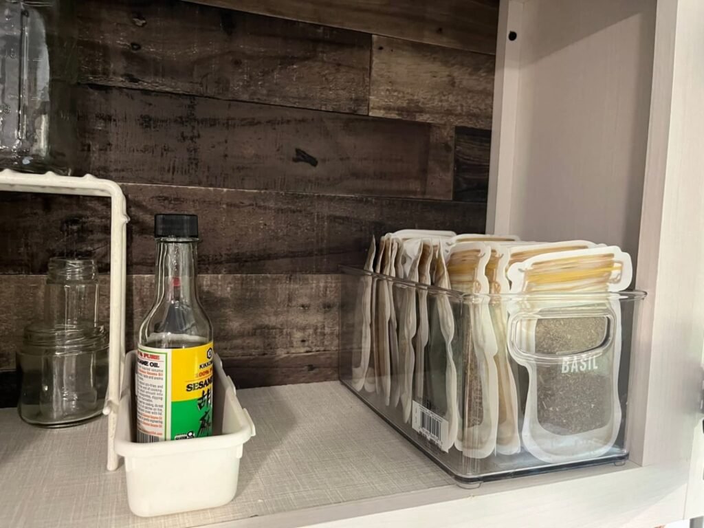 clear pantry bins and labeled spice storage in RV cabinet